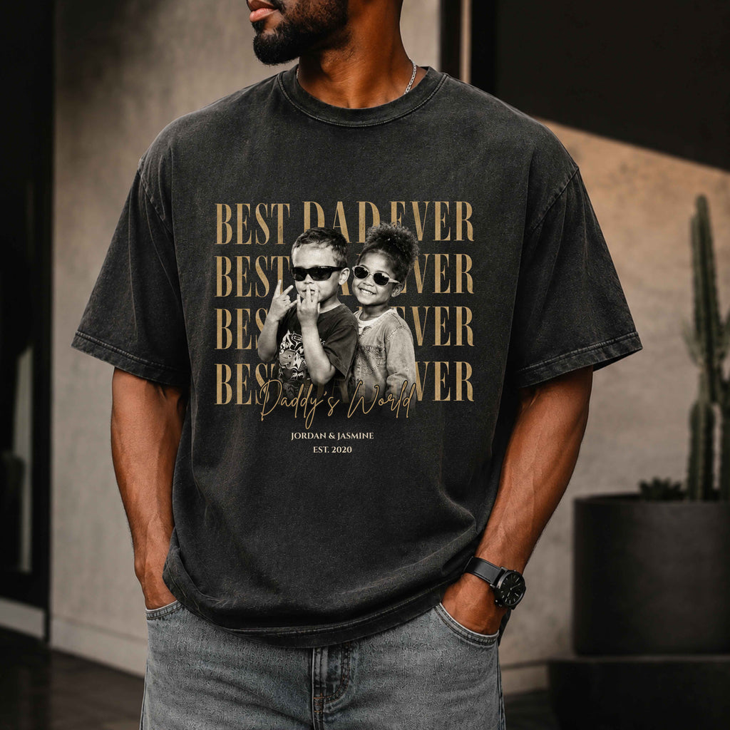 Man wearing a black t-shirt with a graphic of two children and text 'Best Dad Ever' in a room.
